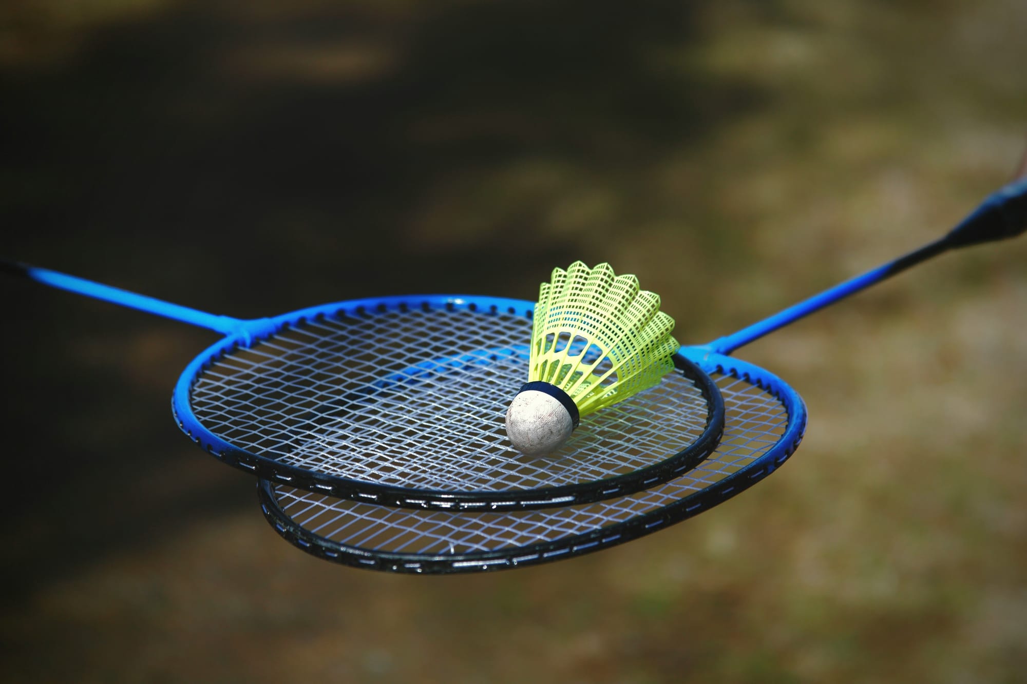Zwei Badmintonschläger bzw. Rackets, die ein Federball (aka. Shuttlecock) halten